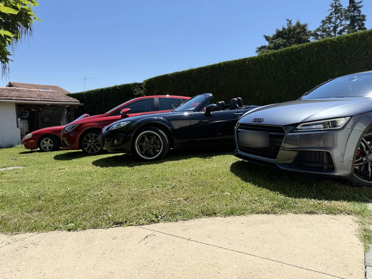 Mazda MX-5 NC noire décapotée, de profil, dans l'alignement.