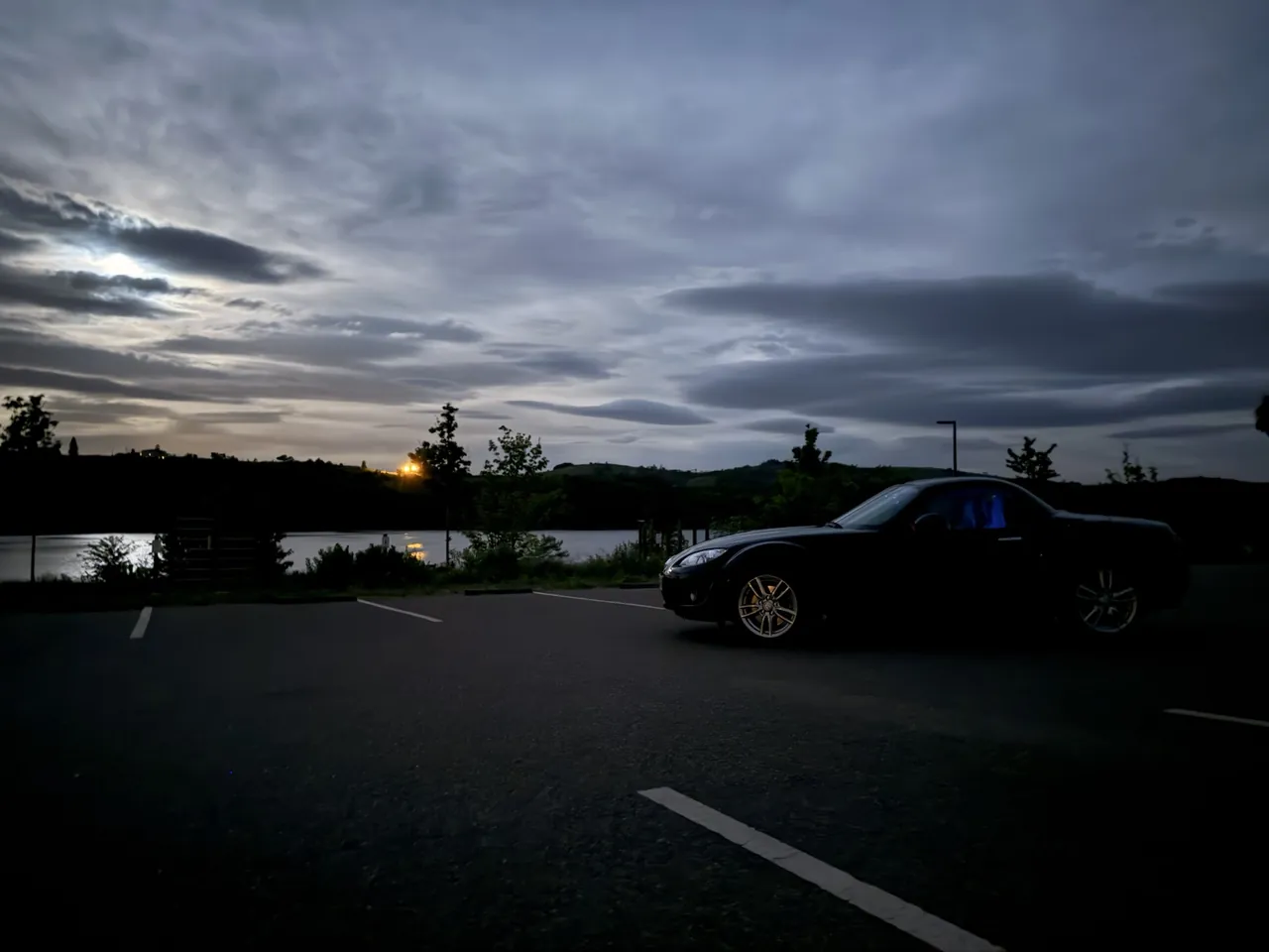 Mazda MX-5 NC noire de profil au bord du lac de Villerest au crépuscule.